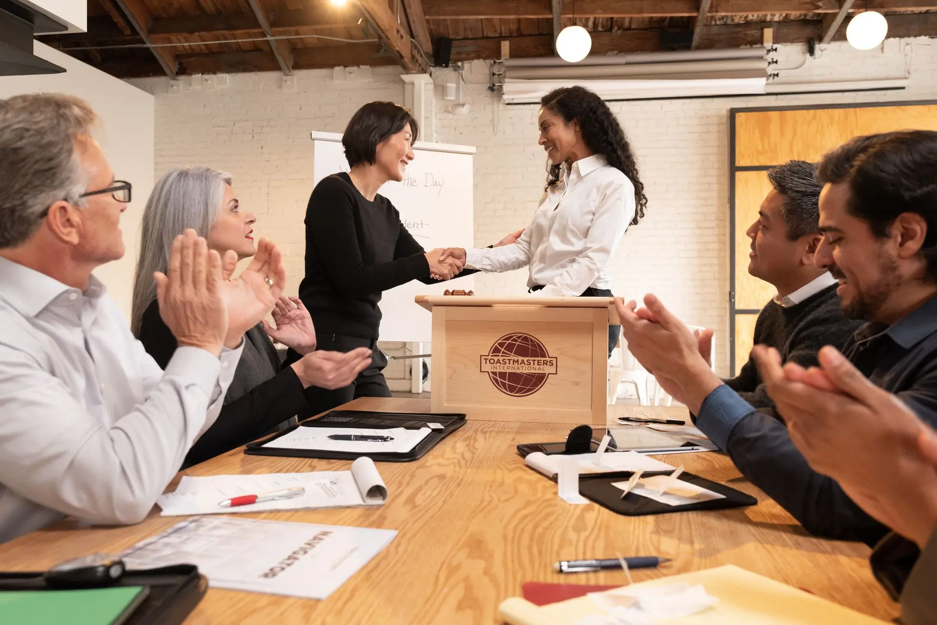 Confident speaker delivering speech, engaging audience, Toastmasters session.